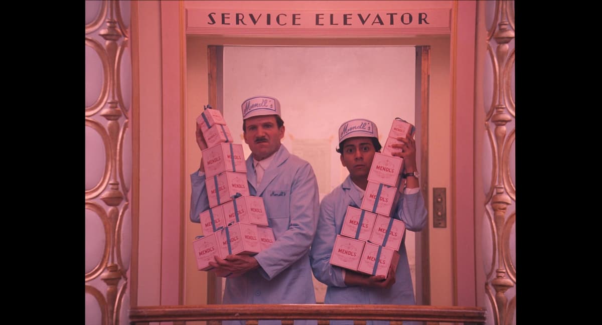 Gustav and Zero holding boxes in the hotel